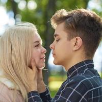 The boy looks tenderly at girl, hands clasped her face and wants to kiss. Concept of teenage love and first kiss photo