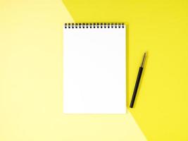 Blank notepad white page on yellow desk, color background. Top view, empty space for text. photo