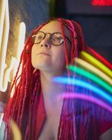 Girl in neon lights, beautiful woman in sunglasses, with pink hair, with dreadlocks pigtails photo