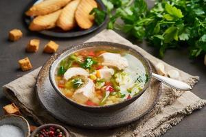 Homemade chicken soup with vegetables, crouton, broccoli on a dark brown background, side view photo