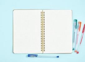 Blank notepad page in bullet journal on blue office desktop. Top view of modern bright table with notebook. Mock up, copy space photo