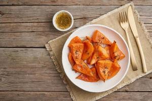 roasted pumpkin, pieces in plate with oil, thyme, honey and seasonings photo