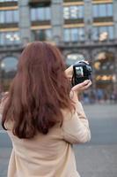 Unrecognizable person standing with his back turned and photographs sights, woman with long thick dark hair, tourist in center of St. Petersburg. Focus on camera