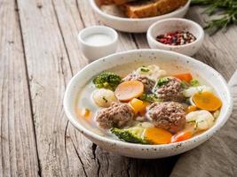 sopa de albóndigas en un plato blanco sobre una vieja mesa gris rústica de madera, vista lateral foto