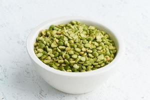 guisantes verdes en un tazón blanco sobre fondo blanco. cereales secos en taza, comida vegana. vista lateral