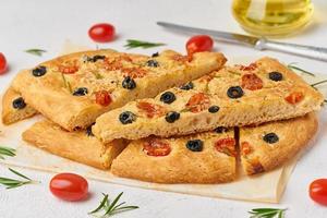 Focaccia, pizza, sliced italian flat bread with tomatoes, olives and rosemary