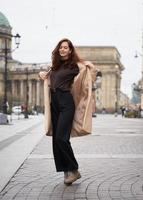 Beautiful funny naughty stylish fashionable happy girl dancing on streets of St. Petersburg city. Charming smiling woman with long dark hair, vertical photo