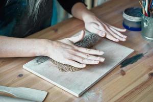 mujer haciendo patrón en placa de cerámica, primer plano de las manos, enfoque en las palmas