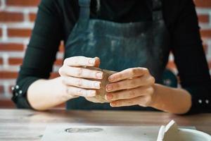 Woman making pottery, hands closeup, blurred background, focus on potters, palms with pottery. Concept for woman in freelance, business, hobby. Turning hobbies into cash and passion into job.