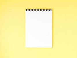 página en blanco del bloc de notas en blanco en el escritorio amarillo, fondo de color. vista superior, espacio vacío para texto. foto