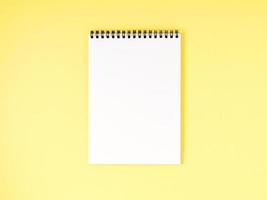 Blank notepad white page on yellow desk, color background. Top view, empty space for text. photo