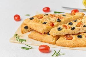 Focaccia, pizza, sliced italian flat bread with tomatoes, olives and rosemary photo