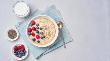 Oatmeal with berries, chia, maple syrup and glass of milk photo