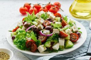 Greek Salad with feta and tomatoes, dieting food on white background closeup photo