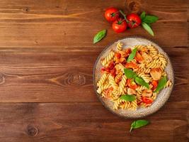 fusilli pasta with tomato sauce, chicken fillet with basil leaves photo