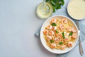 Pasta spaghetti with fried shrimps, bechamel sauce, mint leaf on blue table photo