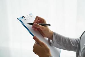 Unrecognizable person writing on clipboard, copy space photo