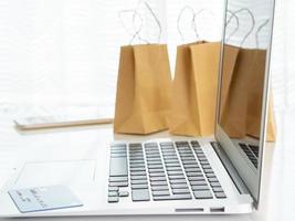 paquetes artesanales con compras, teléfono inteligente portátil, tarjeta de crédito en la mesa frente a la ventana, concepto de compras en línea foto