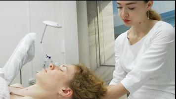 um massagista dá a uma mulher uma massagem facial profissional. a sala de massagem realiza um procedimento de rejuvenescimento. filmagem full hd de alta qualidade