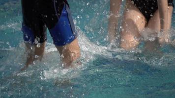 Seleccione el enfoque en la parte inferior del cuerpo para niños pequeños que juegan en la piscina. video