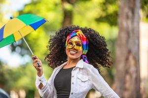 Young curly hair woman celebrating the Brazilian carnival party with Frevo umbrella on street. photo