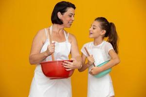 Mother's day concept. Daughter and mother preparing a recipe on yellow background photo