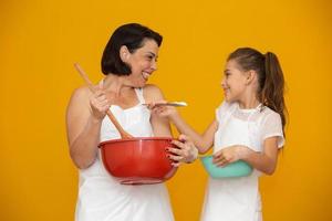 concepto del día de la madre. hija y madre preparando una receta de fondo amarillo foto