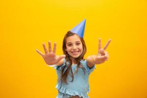 Cute little girl celebrates birthday. Seven years old. Closeup portrait on yellow background. photo
