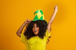 Brazil supporter. Brazilian woman fan celebrating on soccer or football match on yellow background. Brazil colors. photo