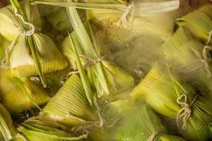 Brazilian sweet corn dessert called Pamonha. Festa Junina Party. Brazilian culture. Cooking in the pan. Wood burning stove. photo