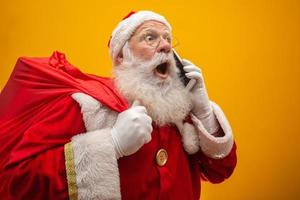 Holly jolly x mas Santa in headwear, costume, black belt, white gloves brings gifts for kids, prepared to celebrate, sale promotion, winter december, chatting on telephone. Santa talking on the phone photo