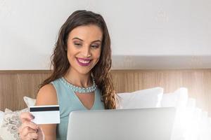 mujer joven con tarjeta de crédito y usando computadora portátil. concepto de compras en línea foto