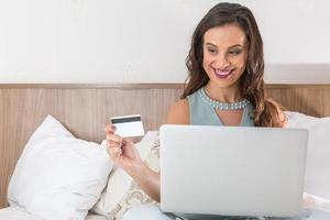 mujer joven con tarjeta de crédito y usando computadora portátil. concepto de compras en línea foto