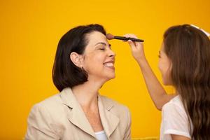 Happy loving family. Mother and daughter are doing make up. mom and her young daughter are preparing to make mikej together. photo