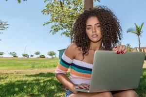Young black woman using laptop computer in park photo