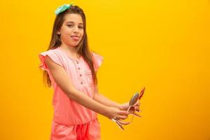 The child is holding a lollipop. Childish joy is sweetness. Little girl on yellow background. photo