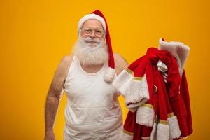 santa sosteniendo su ropa antes o después de entregar los regalos. la ropa de papa noel traje. foto