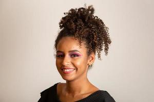 joven mujer afroamericana con cabello rizado mirando a la cámara y sonriendo. linda chica afro con cabello rizado sonriendo mirando a la cámara. foto