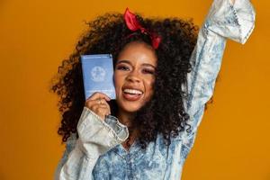 Beautiful curly-haired girl holding a work card. On yellow background. photo