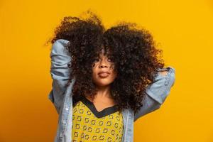 Beauty portrait of african american woman with afro hairstyle and glamour makeup. Brazilian woman. Mixed race. Curly hair. Hair style. Yellow background. photo