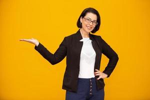 Beautiful middle age business woman smiling and looking at the camera pointing with hand to the side. photo