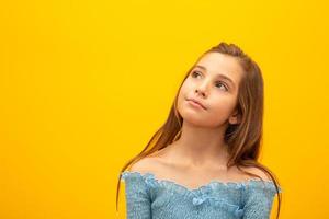 Beautiful female half-length portrait isolated on yellow studio background. Little emotional Brazilian girl. Facial expression, human emotions, advertising concept. Thinking, looking up. photo