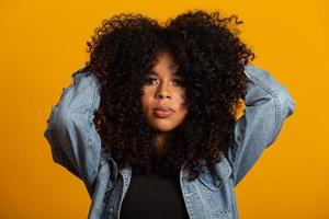 joven mujer afroamericana con cabello rizado mirando a la cámara y sonriendo. linda chica afro con cabello rizado sonriendo mirando a la cámara. foto