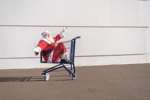 carro de supermercado con santa claus dentro. compras por concepto de navidad. foto