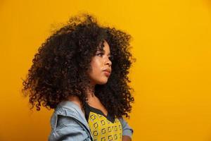 Beauty portrait of african american woman with afro hairstyle and glamour makeup. Brazilian woman. Mixed race. Curly hair. Hair style. Yellow background. photo