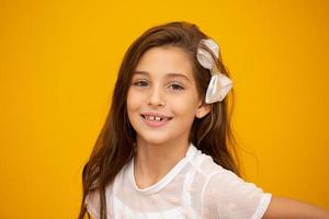 Portrait of a happy smiling child girl in yellow background. photo