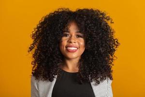 Young afro-american woman with curly hair looking at camera and smiling. Cute afro girl with curly hair smiling looking at camera. photo