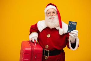 Santa Claus with his suitcase. Holding a brazilian passport. New Year's travel concept. Santa Claus at the airport. photo
