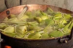 postre de maíz dulce brasileño llamado pamonha. fiesta de fiesta junina. cultura brasileña. cocinando en la sartén. estufa de leña. foto