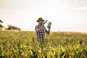 Agronomist holds tablet touch pad computer in the corn field and examining crops before harvesting. Agribusiness concept. Brazilian farm. photo